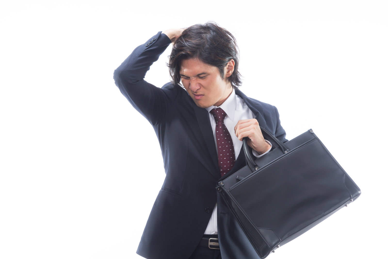 体臭を気にして困った表情で頭を抱えるスーツ姿の会社員［モデル：竹田匡宏］