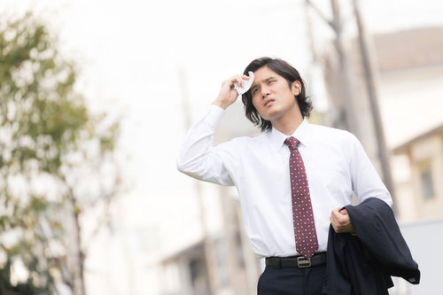 暑くて上着を脱ぐサラリーマン（営業中の外回り）