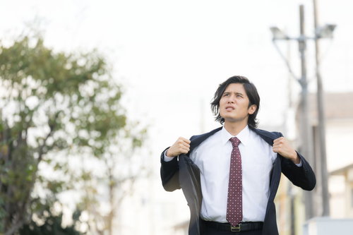 熱くても脱げないスーツ姿のサラリーマン男性