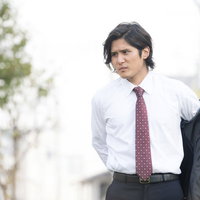 スーツの上着を脱ぎ始める会社員男性の体臭対策の写真