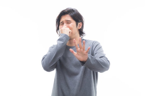耐え難い悪臭で顔を背けてストップポーズをとる男性