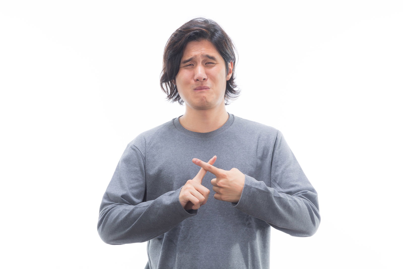 グレーのニットを着て困った表情で指を差す男性［モデル：竹田匡宏］