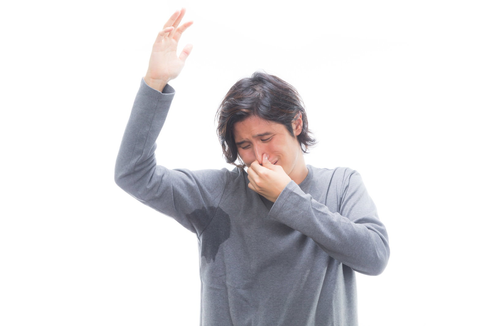 グレーの服を着た男性が片手を上げて鼻をつまんでいる様子［モデル：竹田匡宏］