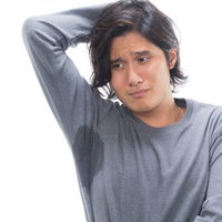 脇汗とワキガに悩む、困った表情の男性が頭を抱えるの写真