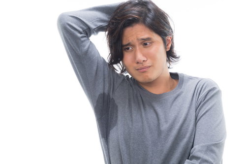 脇汗とワキガに悩む、困った表情の男性が頭を抱える