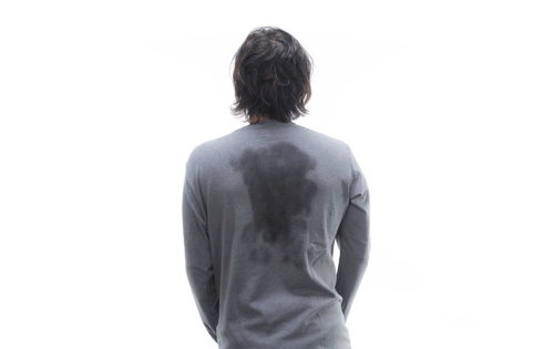 背中の大量の汗ジミが広がった男性の後ろ姿