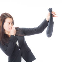 男性用靴下の悪臭に鼻をつまむ女性のポートレートの写真