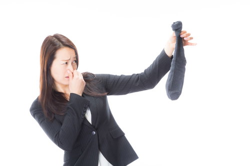 男性用靴下の悪臭に鼻をつまむ女性のポートレート