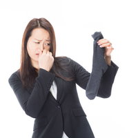 靴下から発する悪臭で鼻をつまむオフィスレディの写真