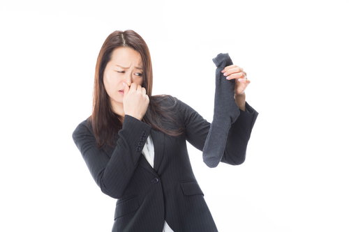 靴下から発する悪臭で鼻をつまむオフィスレディ