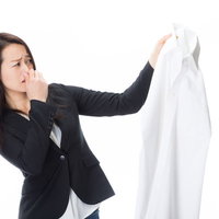 悪臭がする男性のワイシャツを片手に露骨に嫌がる女性社員の写真