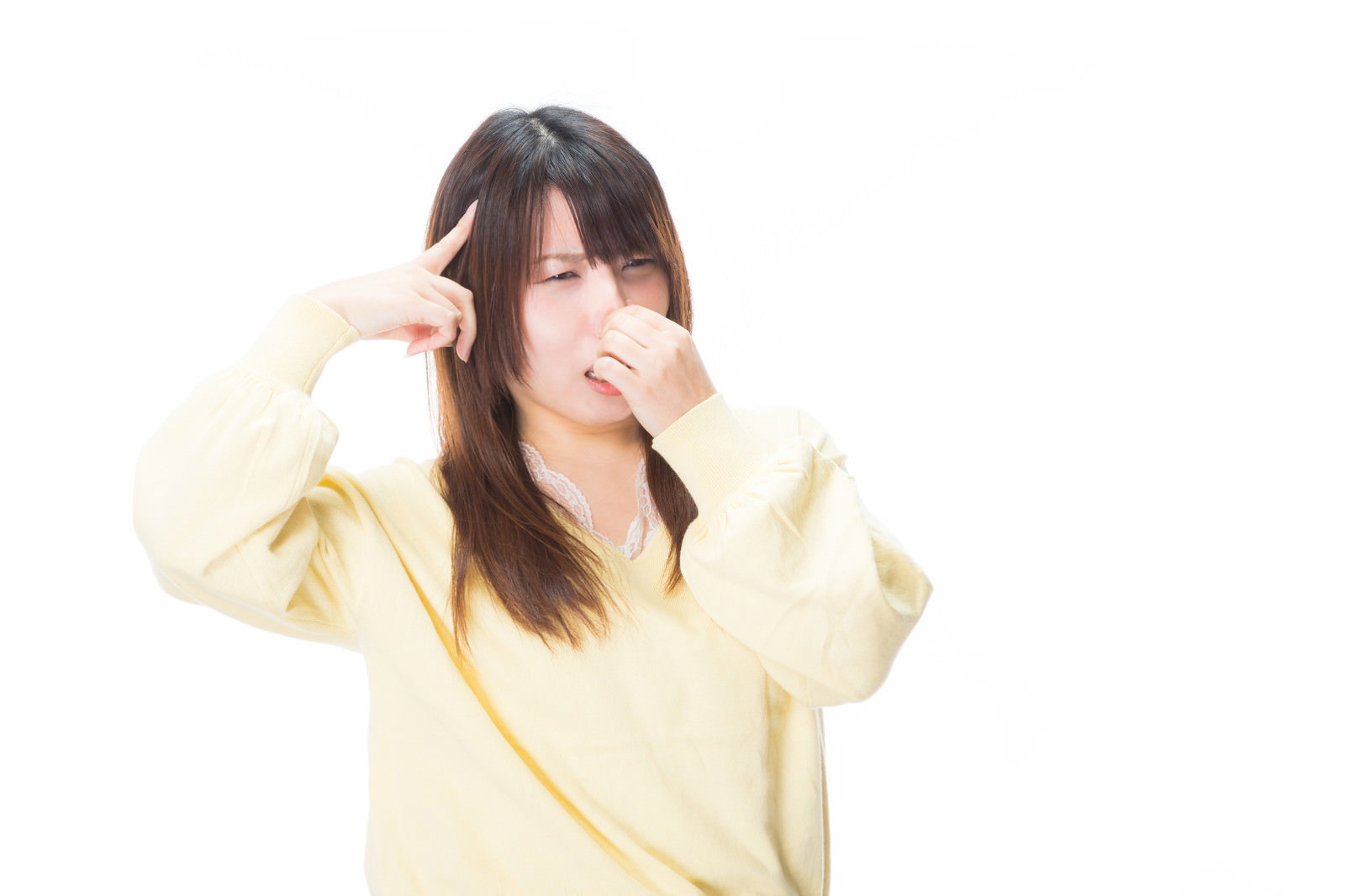 黄色い服を着た女性が頭を抱え、鼻を覆って困っている様子［モデル：Lala］