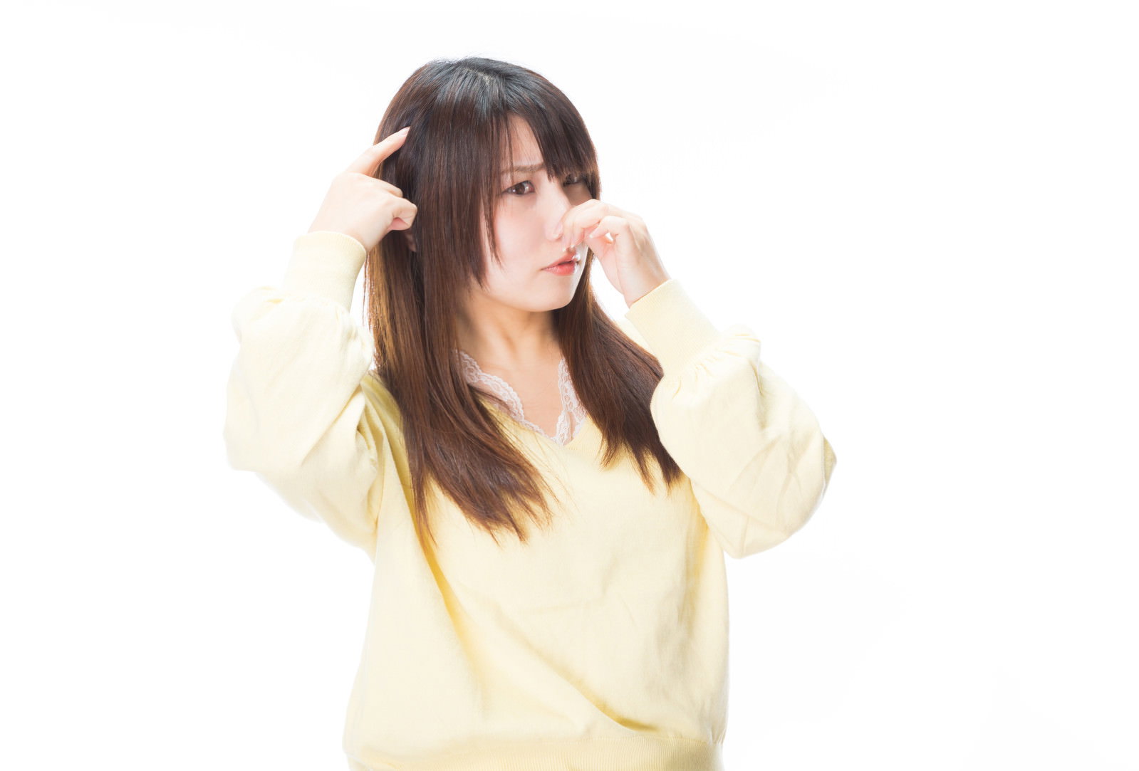両手で頭を抱えて苦痛な表情を浮かべる黄色い服の女性［モデル：Lala］