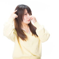 頭が痛くなるほどの悪臭を嗅ぐ黄色いトップスの女性の写真