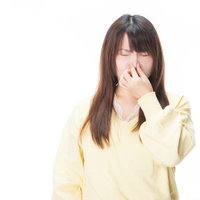 衝撃的なにおいに思わず鼻をつまんで目を閉じる女性の写真
