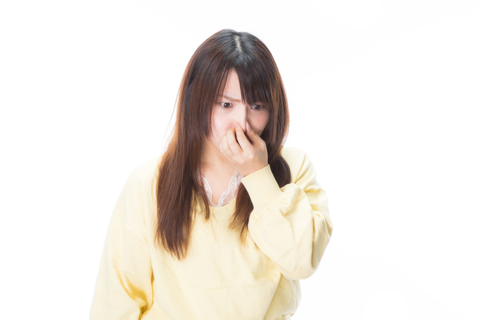 黄色いニットを着た女性が右手で鼻をつまんで嫌がっている様子［モデル：Lala］