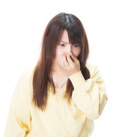 臭いの根源を凝視する女性が鼻をつまんで嫌がる表情の写真