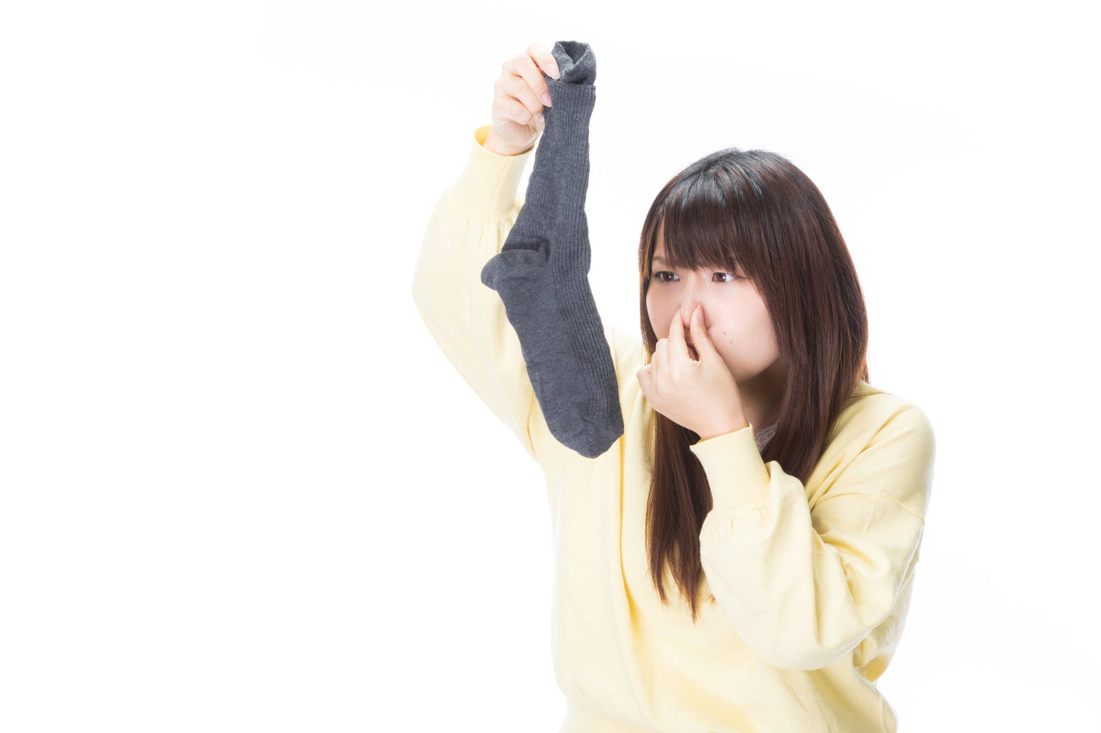 鼻をつまんで顔をしかめる黄色い服の女性［モデル：Lala］