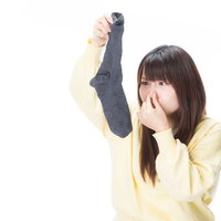 使用済みの男性用靴下から強烈なにおいが・・・鼻をつまむ女性の写真