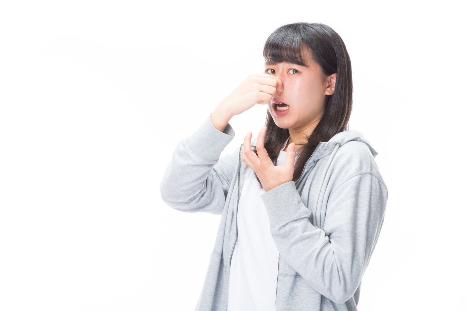 白いシャツを着た女性が悪臭で鼻をつまんで嫌がっている様子［モデル：Mizuho］