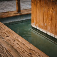草津温泉の木造足湯の風情ある景観と温泉の透明な湯の写真