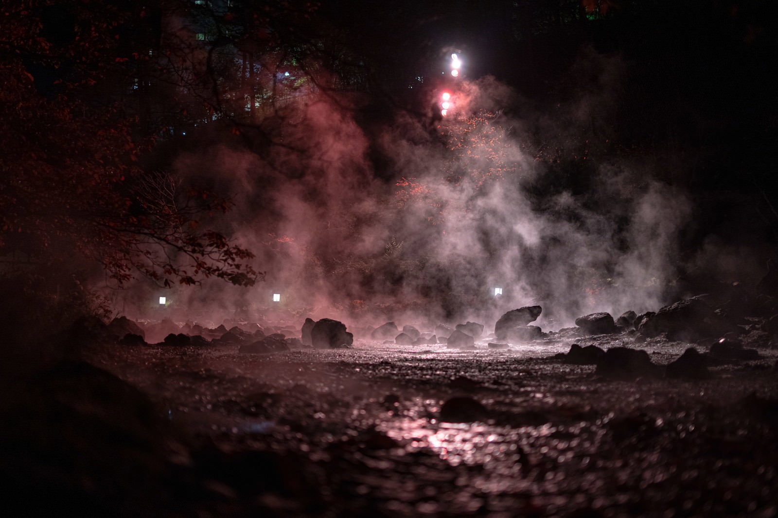 夜の西の河原公園で立ち上る湯気がピンク色にライトアップされた温泉風景