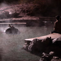 西の河原公園で夜間にライトアップされた足湯に浸かる恋人たちの写真