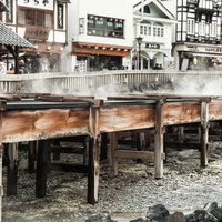 草津温泉の湯畑に並ぶ木造の湯樋の側面と温泉街の写真