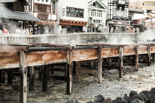 草津温泉の湯畑に並ぶ木造の湯樋の側面と温泉街