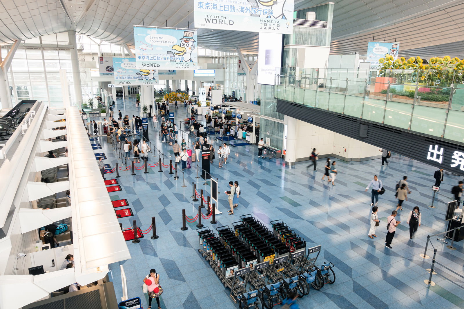 羽田空港第三ターミナルの広い通路を行き交う旅行者たち