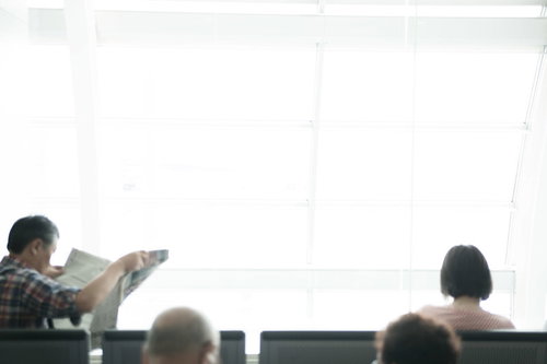 空港の待機ロビーで資料を確認するビジネス乗客たち