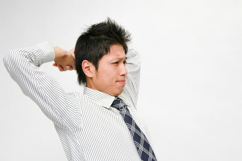 ネクタイ姿で背伸びするシャツの社員のストレッチ