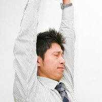 両腕を上げてストレッチする会社員の男性のリラックス姿の写真