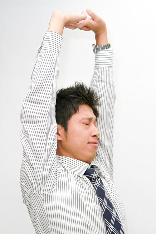 両腕を上げてストレッチする会社員の男性のリラックス姿