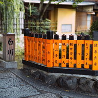 祇園白川の石畳沿いに並ぶ名前が入った奉納柵と巽橋の写真