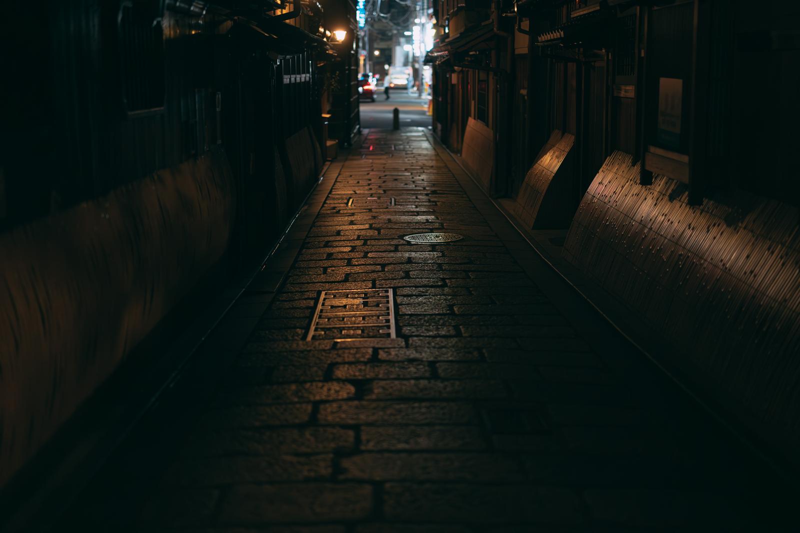 京都祇園白川の夜間の路地裏。石畳に映る光と両側の伝統建築