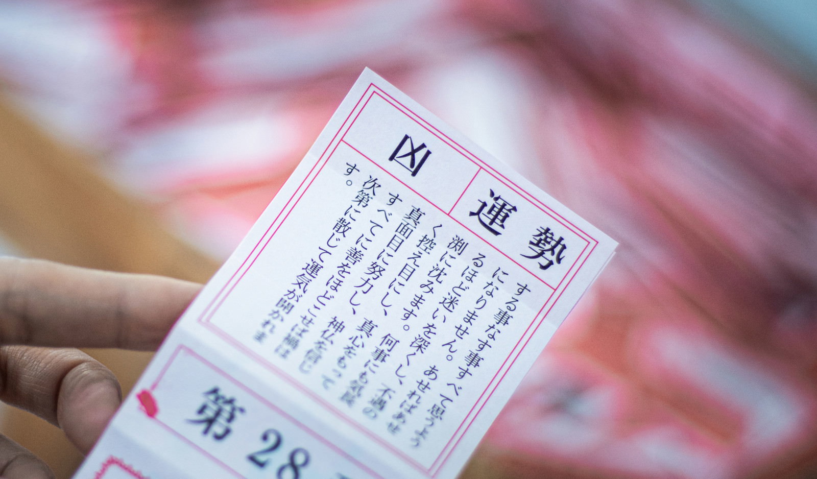 手に持たれたおみくじに「凶」の文字が書かれている