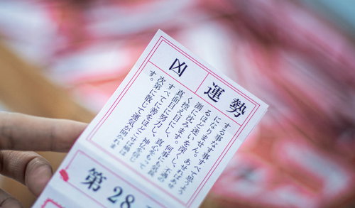 おみくじで引いた運勢「凶」の結果を手に持つ場面