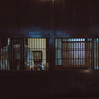 古民家の格子戸の隙間越しに暗闇を覗き見る女性の写真