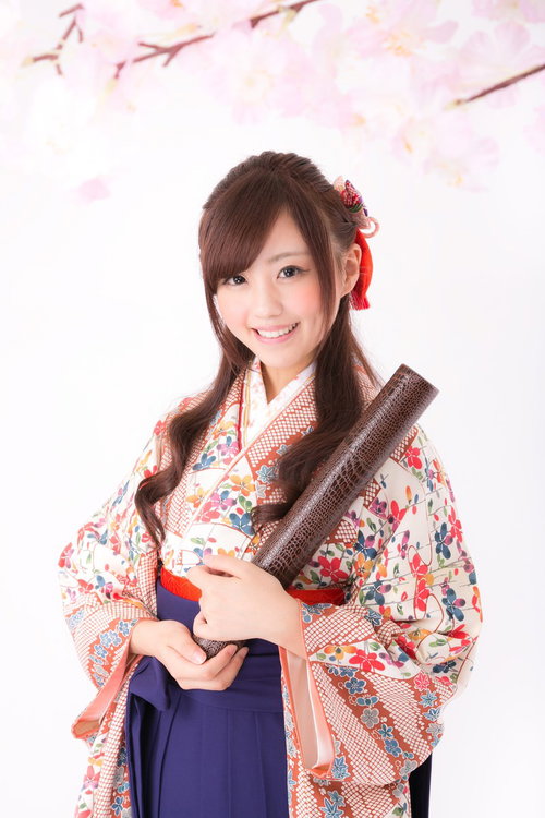 卒業証書を持った花柄の着物に紺色の袴姿の女性