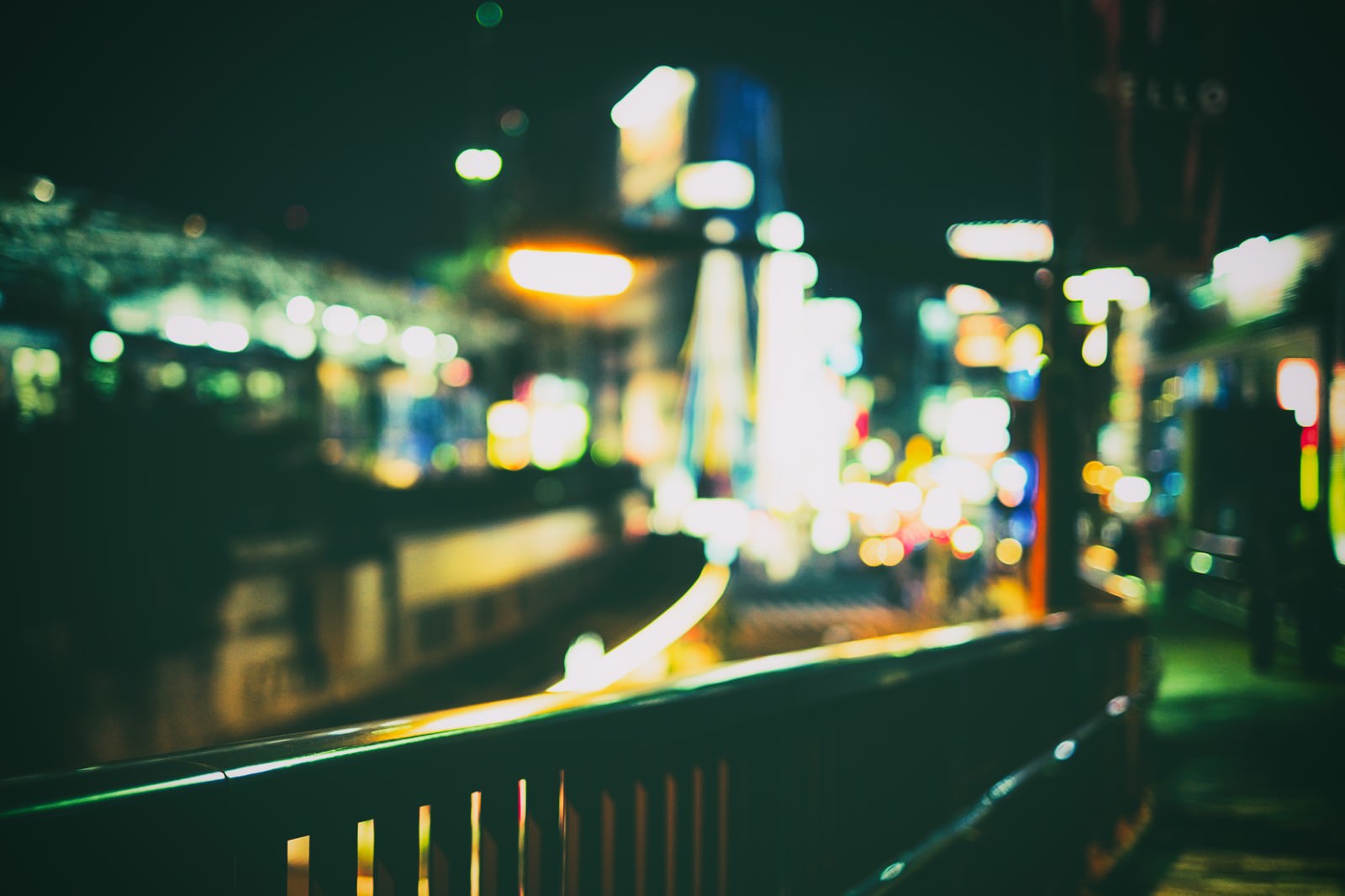 手前の手すりにピントを合わせ、背景の夜の街並みがボケている写真