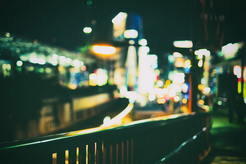 ボケ味ある夜の街のネオンと手すり、都市の光と奥行き