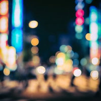 ネオン灯りが丸ボケになる夜間の繁華街の夜景の写真