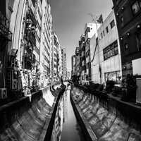 都市部を流れる渋谷川のモノクロ風景、高層ビルが映り込む白黒の写真