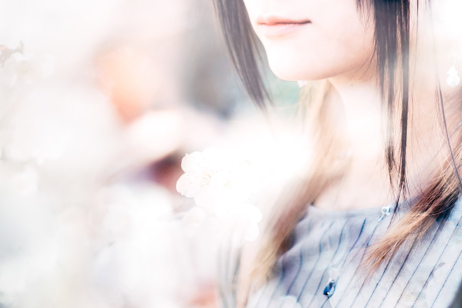 女性の口元のアップと白い花が写った写真