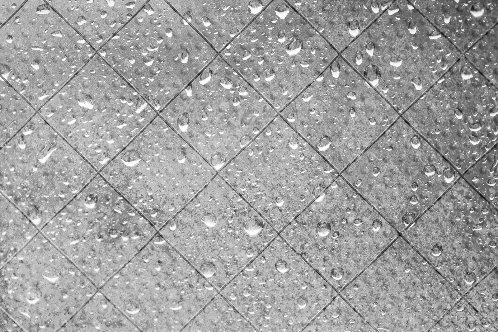 透明な窓ガラス表面に無数の雨粒が付着している様子