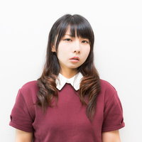 白い襟の赤紫色の半袖シャツで正面を向く黒髪の若い女性の写真