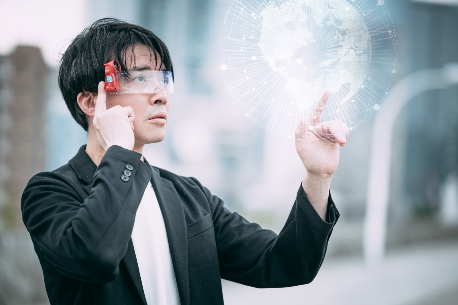 ARグラスを装着し指先でホログラムの地球に触れる黒ジャケットの男性［モデル：金子周平］