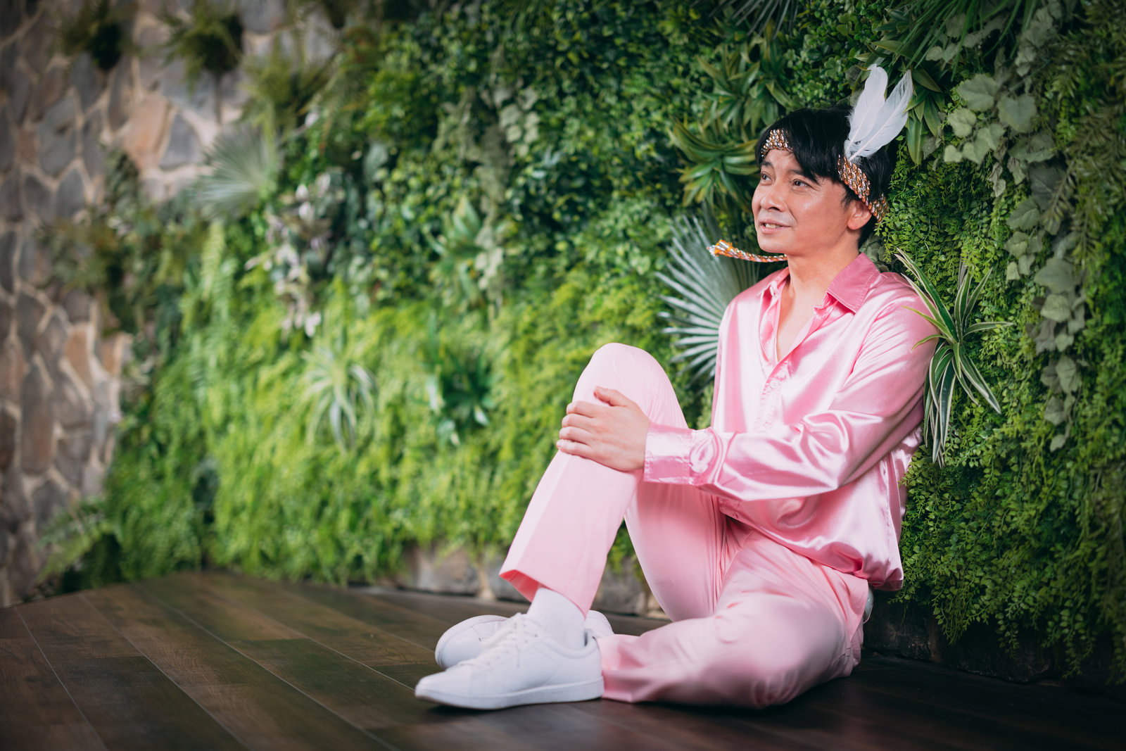 ピンク色のシャツを着て、フェザー飾りを付けた男性がアイドル志望について語っている［モデル：金子周平］