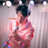 ステージ上で熱唱する男性アイドル、ピンク照明の中でマイクを握るの写真